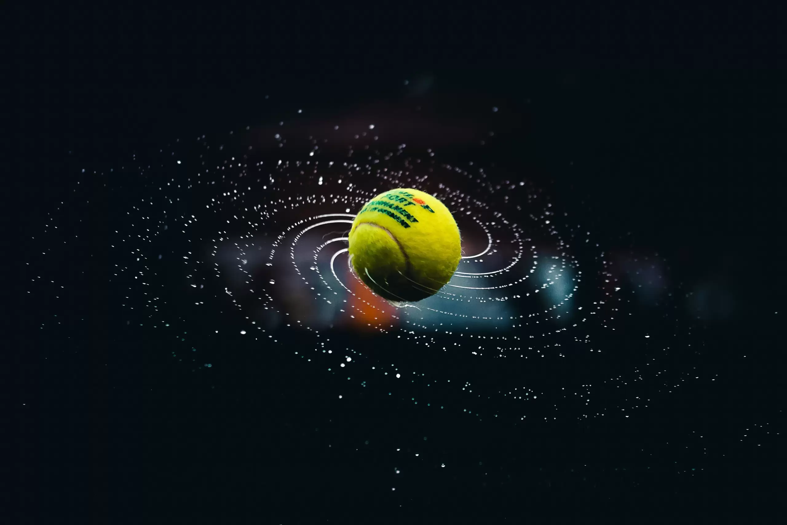 Minge de tenis rotindu-se rapid, cu picături de apă formând o spirală, pe fundal întunecat