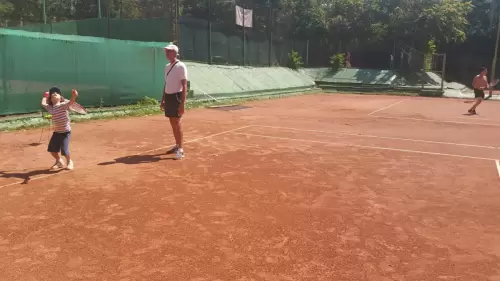 Antrenor de tenis corectează și analizează lovitura de rachetă a unui copil în timpul antrenamentului
